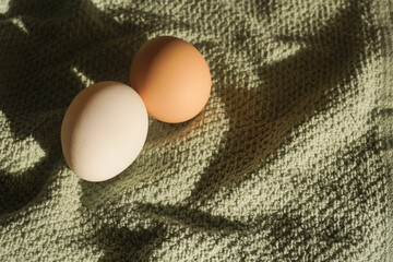 two chicken eggs on a green towel. Home cooking concept