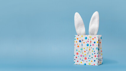 Easter sale, shopping, gift. Easter bunnys ears in a shopping bag, nice funny photo copy space for your text. Blue background