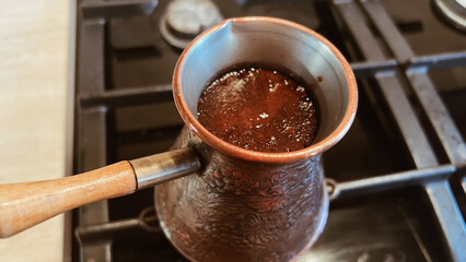 Top view of coffee in ibrik. Close-up Arabice coffee brewed in brass vintage jezve. Preparing...