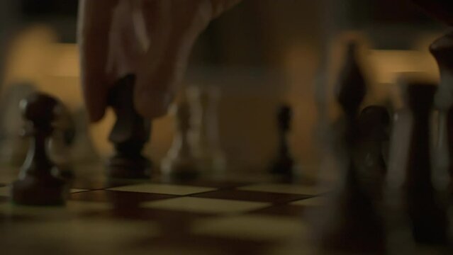 In a chess match, an experienced player decisively moves his piece, creating a memorable image. In an authentic chess hall, a duel takes place between two professionals striving for victory