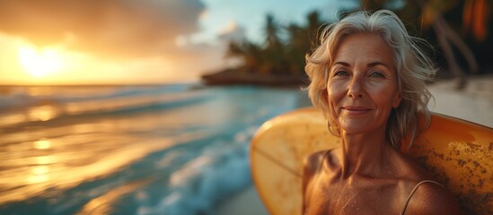 A banner with beautiful mature woman 50-60 years old standing with a surfboard on the summer sunny warm beach on a sunset