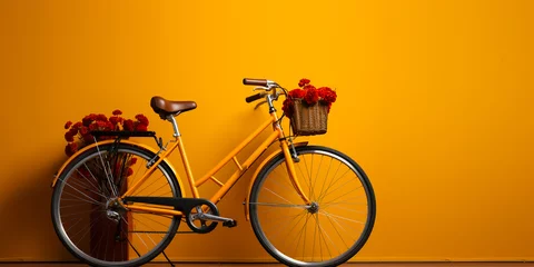 Poster Yellow bicycle with flowers parked next to a yellow wall. Yellow tone. © Rassamee