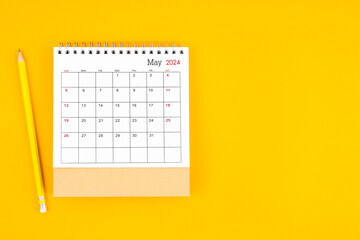 May 2024 desk calendar and wooden pencil on yellow color background.