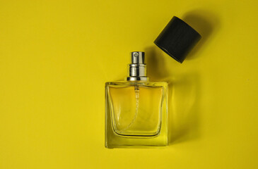 bottle of perfume on yellow. transparent empty perfume bottle with an open cap on a yellow...