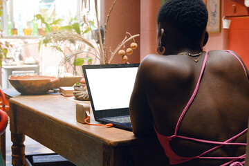 young afro woman at home sitting with laptop working.