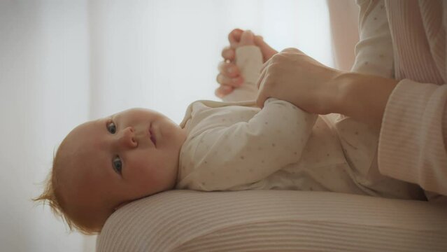 A caring mother enjoys spending time with her newborn baby, playing games and giving massages for his development. She devotes herself, providing her attention and care to the small child