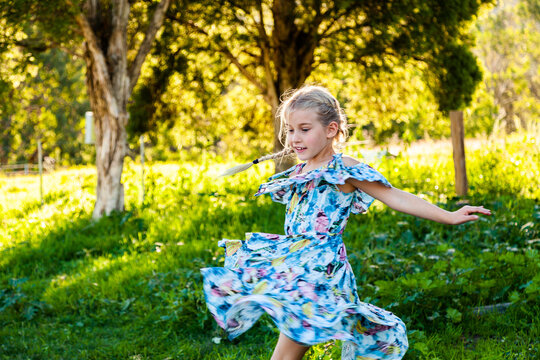 Six year old girl twirling outside in blue dress