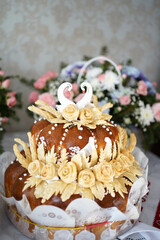 The wedding cake is decorated with white swans on the festive table of the newlyweds