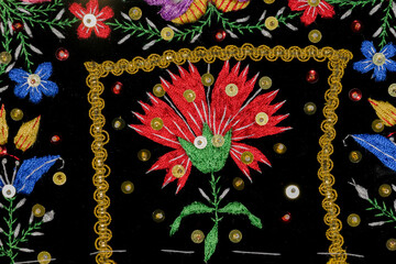 Detail of regional folk costume embroidered with rose, leaves and bright sequins horizontally