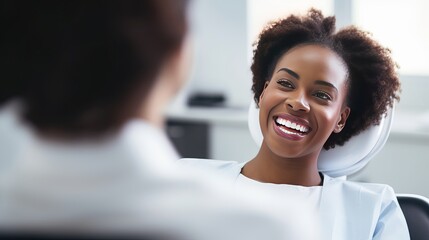 Smiling dentist communicating with African American woman while checking her teeth during dental procedure at dentist's office - obrazy, fototapety, plakaty