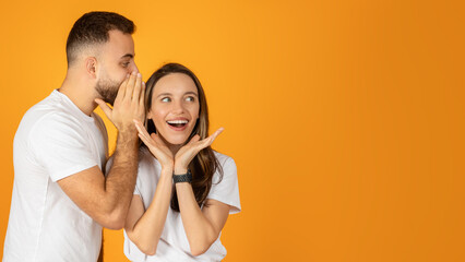 A man whispers a secret into a woman's ear, both wearing white t-shirts