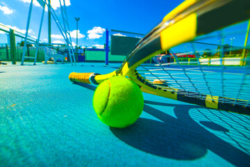 tennis racket and ball on a tennis court on a bright sunny day	