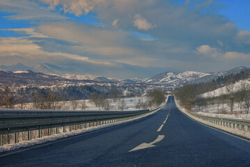 Winter scene of a road and mountains in rural area - 729338020