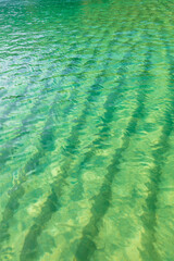 Fototapeta premium Close-up of the crystal clear turquoise waters, with natural ripples caused by the wind. Water texture. Beautiful shades of green in the sea water.