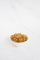 Raisins in a white bowl on a marble table