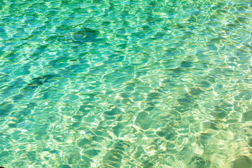 Close-up of the crystal clear turquoise waters, with natural ripples caused by the wind. Water texture. Beautiful shades of green in the sea water.
