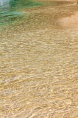 Sea wave reaching the sand of the paradisiacal beach during a beautiful day of sun and turquoise water.