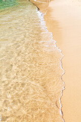 Sea wave reaching the sand of the paradisiacal beach during a beautiful day of sun and turquoise water.