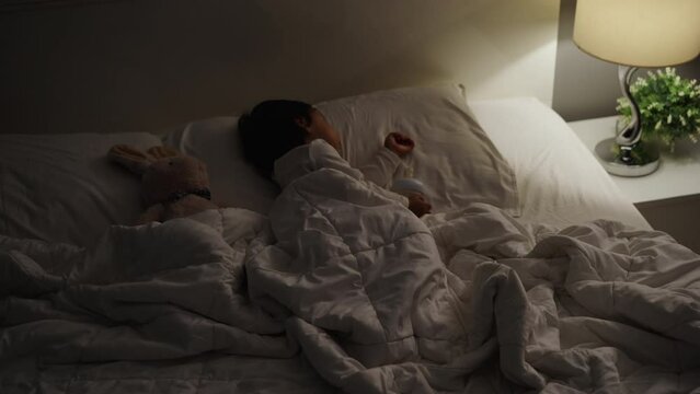 panning shot of toddler baby sleeping on a bed after drinking milk bottle at night