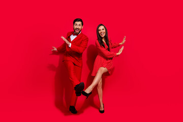 Full size portrait of positive crazy partners have good mood xmas eve dancing isolated on vivid red...