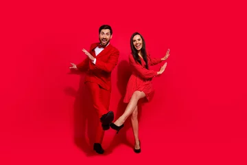 Fototapeten Full size portrait of positive crazy partners have good mood xmas eve dancing isolated on vivid red color background © deagreez