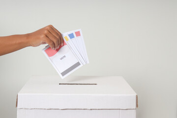Close up of hand inserting and putting the voting paper into the ballot box. General elections or...