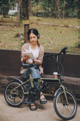 Obraz premium Happy young Asian woman while riding a bicycle in a city park. She smiled using the bicycle of transportation. Environmentally friendly concept.