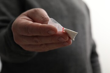 Drug addiction. Man with plastic bag of cocaine on light background, closeup