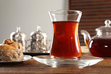 Turkish tea and sweets served in vintage tea set on wooden table, closeup