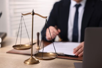 Notary stamping document at wooden table in office, focus on scales of justice