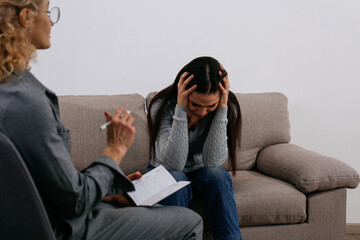 Therapy session concept. Young woman getting a professional help from an adult female psychiatrist...