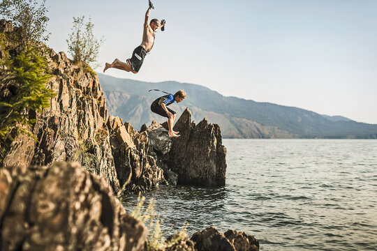 Father and son jumping off a cliff into a lake. Sand Point, Idaho, USA