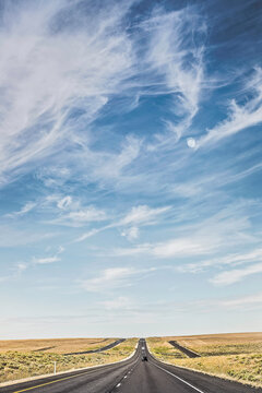 Straight road through empty landscape with big blue skies.