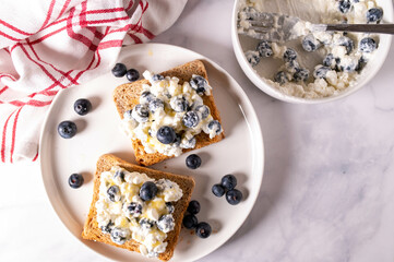 Healthy breakfast sandwich with whole grain toast, cottage cheese, blueberries and honey