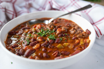Low fat bean soup or bean stew mexican style with kidneybeans, lean ground beef, and vegetables on plate isolated on light background.