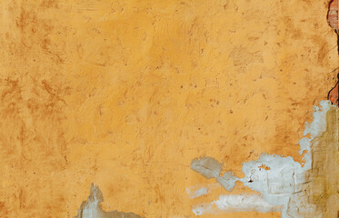 Old orange wall background with cracked plaster texture. Rough plaster wall surface. Grunge wallpaper.