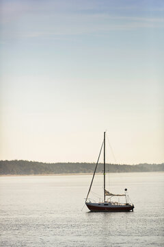Sail boat sailing in bay with land in the background.