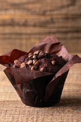 Chocolate dark muffin with chocolate chips and drops on a wooden table 