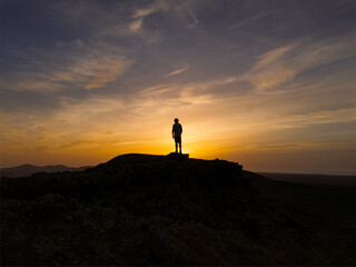 Spectacular sun set image over Volcan Calderon Hondo volcanic crater with silhouetted figure against the setting sun and skyscape near Corralejo, Fuerteventura, Canary Islands, Spain