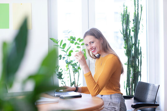 young woman in a room with green plants, home office