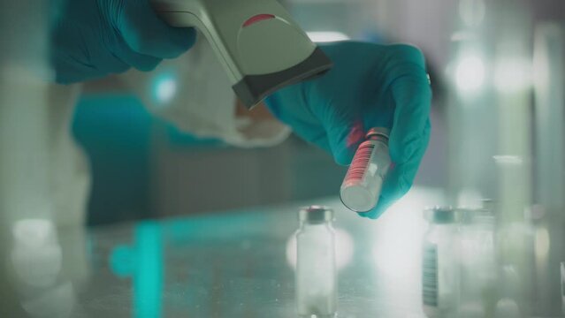 Coat. An experienced scientist wearing nitrile gloves carefully scans drug data in a medical facility. Experienced worker uses laser scanner to record database, pharmaceutical warehouse