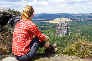 Frau sitzt auf Felsen und schaut in die Ferne, Elbsandsteingebirge, Sachsen, Deutschland