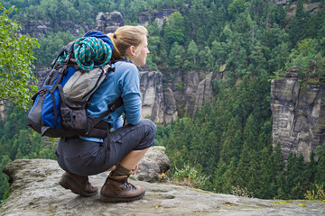 Frau sitzt auf Felsen und schaut in die Ferne, Elbsandsteingebirge, Sachsen, Deutschland