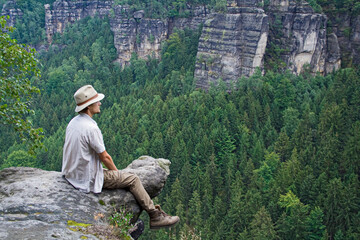 Mann sitzt auf Felsen und schaut in die Ferne, Elbsandsteingebirge, Sachsen, Deutschland