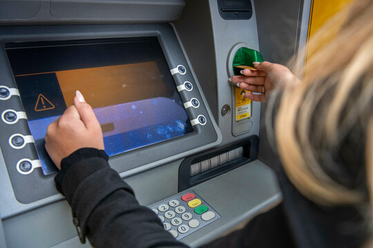 young woman taking money out of her atm, cashmachine