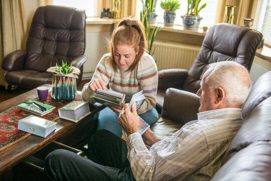 Grand daughter looking at old family photos with Grandad 