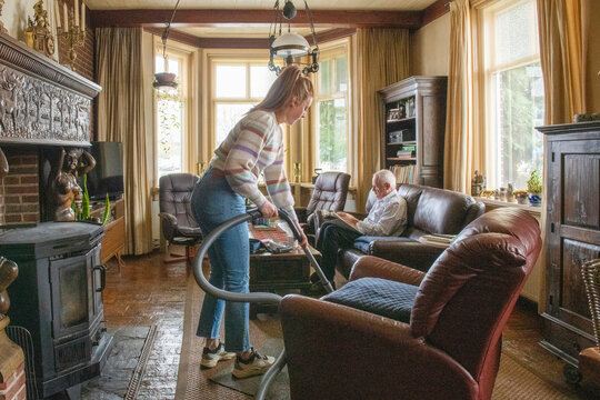 Assisted living helper cleaning elderly mans apartment house