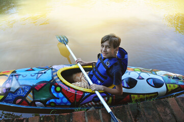 garoto praticando canoagem com canoa no lago, férias escolares  - obrazy, fototapety, plakaty