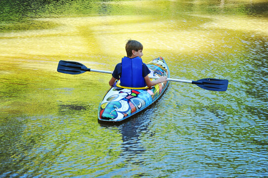 garoto praticando canoagem com canoa no lago, f&eacute;rias escolares 