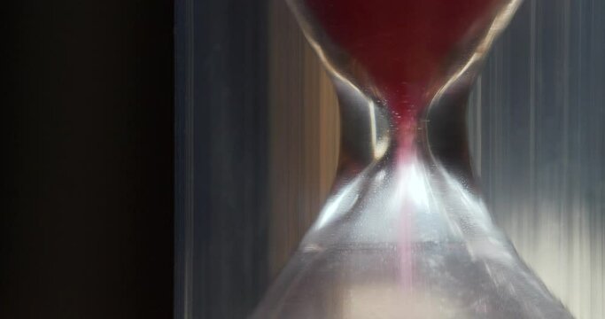 Hourglass. Red sand is falling down. Time is like sand in the endless desert, but remember, your handful is in the hourglass. Cinema 4K 60fps macro shot video